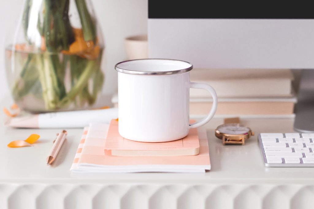 white coffee mug with a silver rim sitting on top of  pink books | my financial freedom 2 | positively jane