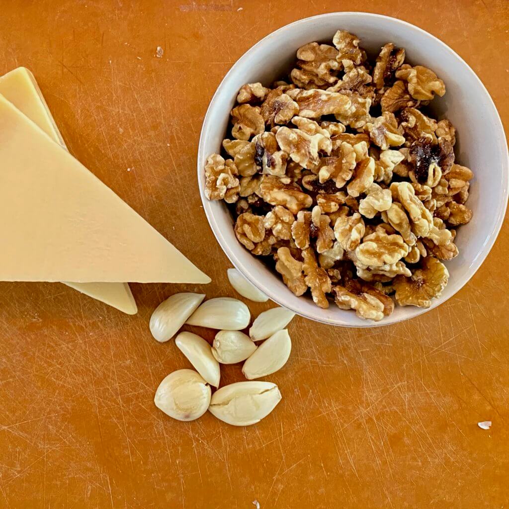 cutting board with parmesean cheese, walnuts and garlic