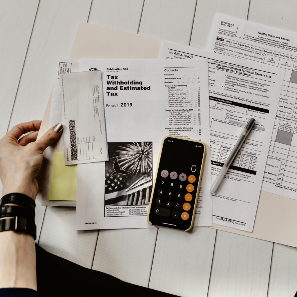 person sitting on the floor looking a a budget with a calculator | benefits of budgeting | Positively Jane  