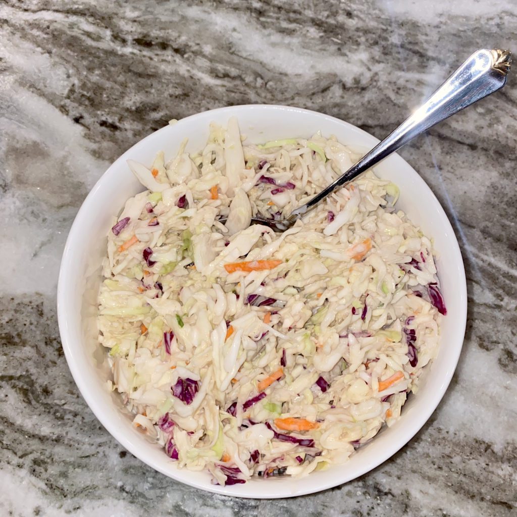 bowl of coleslaw with a spoon in it | chick-fil-a coleslaw recipe | Positively Jane