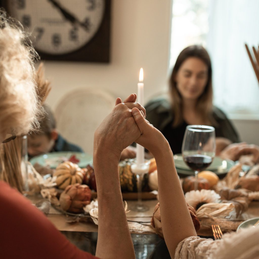 family sitting around a table praying | words of gratitude | Positively Jane  