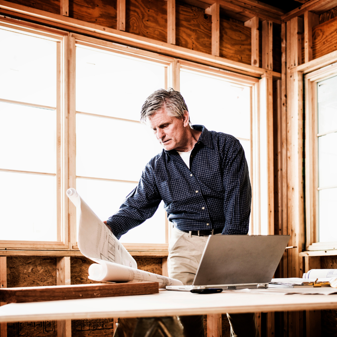 man inside a home that is being build looking at house plans | Choosing a home builder | which builder is best | positively jane