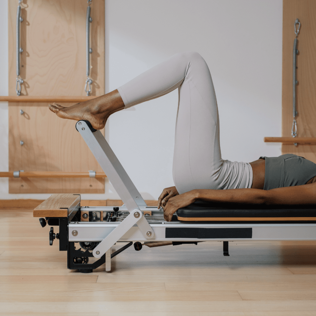 women laying on pilates reformer. All you can see are her legs and the end of the reformer