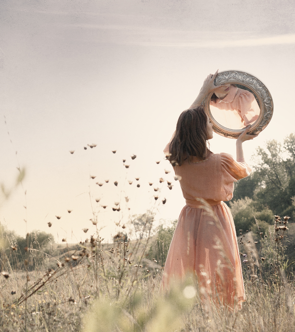 Woman holding a mirror in the air and looking into it