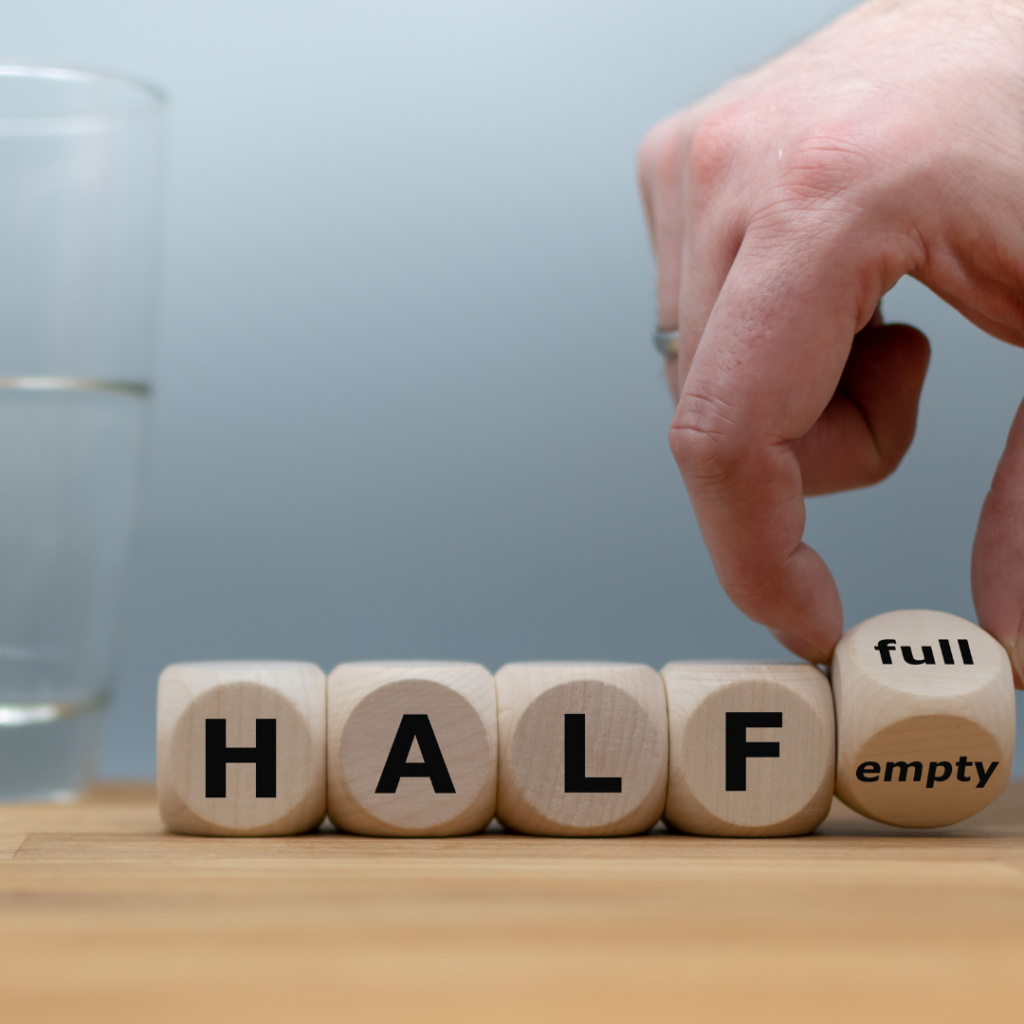 glass half full of water with dice spelling out half full